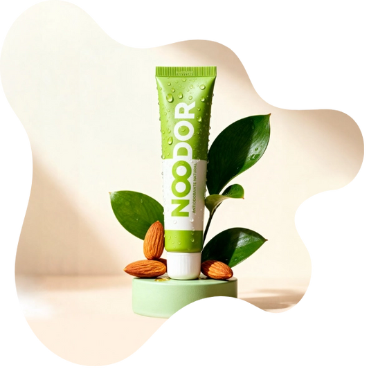 Antiodorante natural Noodor con hojas verdes y almendras, mostrando sus ingredientes vegetales y su fórmula respetuosa con la microbiota.